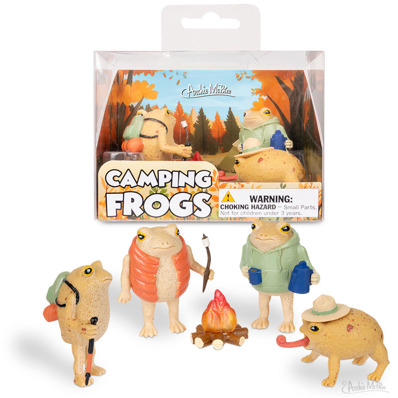 Four vinyl rain frogs in camping gear gather around a campfire, posed before packaging labeled Camping Frogs. This playful set is ideal for fans of outdoor adventures.