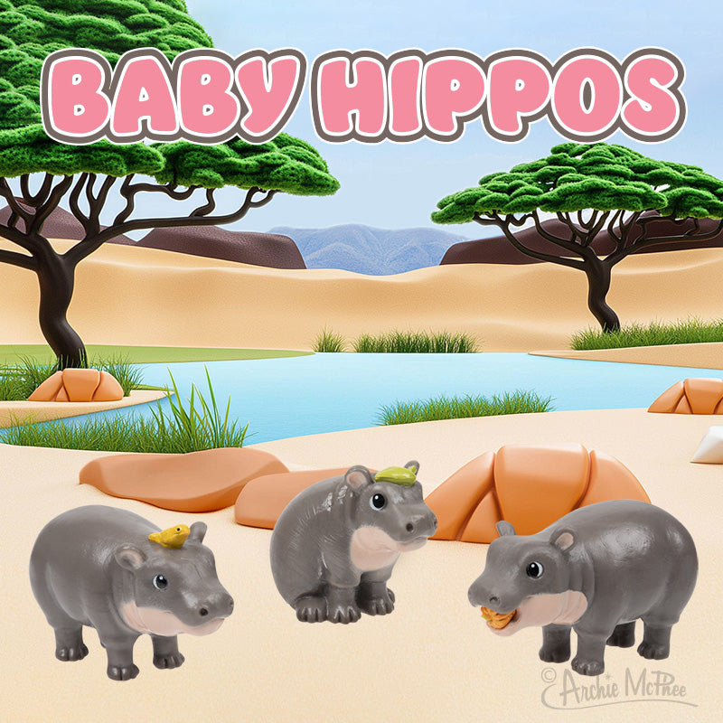 Three Baby Hippos figurines stand on sand by the water, with trees and mountains in the background. Text: Baby Hippos.
